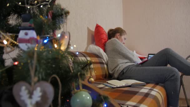 Женщина работает на диване Рождественская елка — стоковое видео