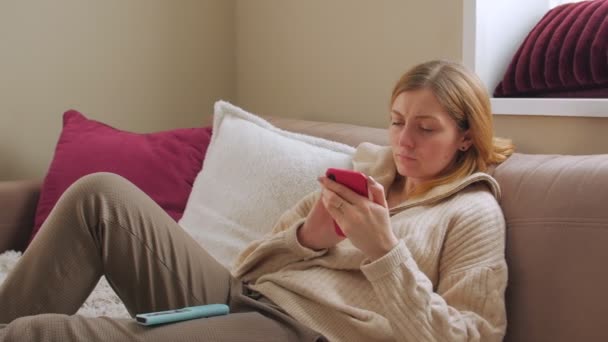 Женщина со смартфоном на диване — стоковое видео