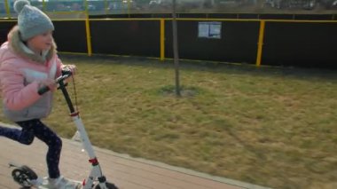 Küçük kız scooter kullanıyor.