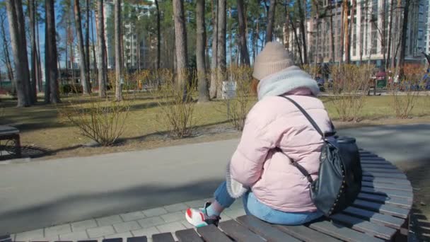 Женщина, сидящая на скамейке в парке — стоковое видео