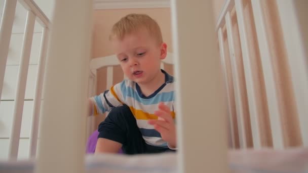 Хлопчик грає іграшки в ліжечко — стокове відео