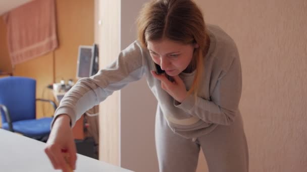 Mujer pinta y habla por teléfono — Vídeos de Stock