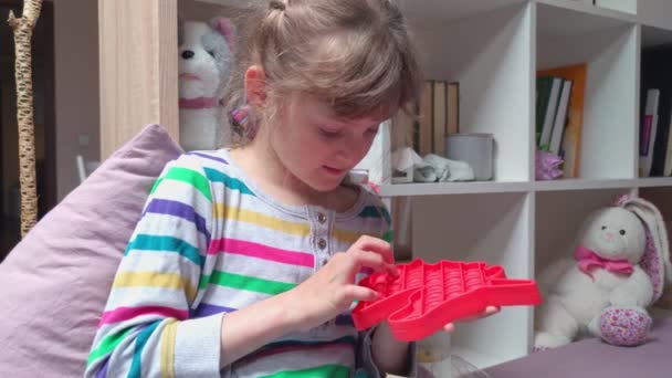 Девочка, играющая с поп-игрушкой — стоковое видео
