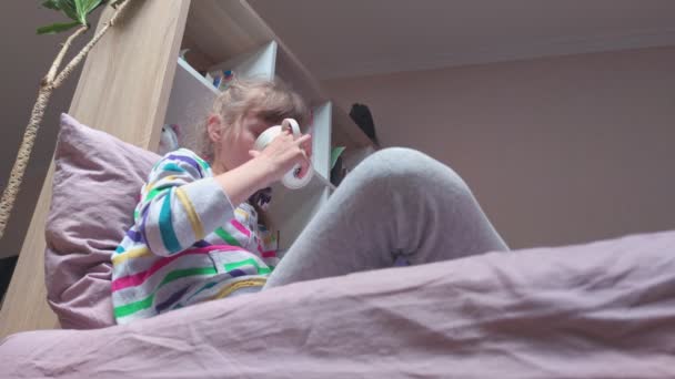 Meisje met een kopje zittend op het bed — Stockvideo