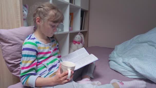 Chica leyendo un libro con una taza — Vídeo de stock