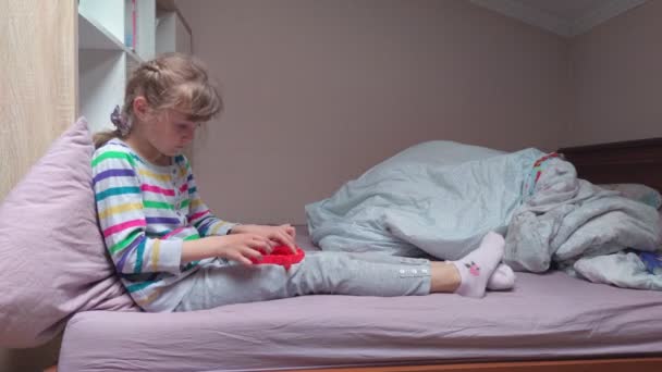 침대에 거품이 나는 장난감을 가지고 있는 소녀 — 비디오