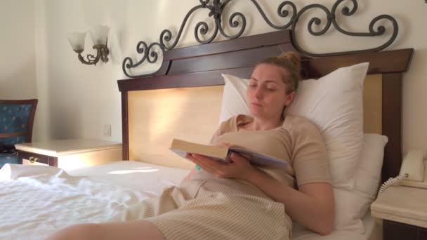 Frau liest Buch im Bett — Stockvideo