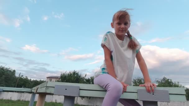 Dívka sedí na hřišti — Stock video