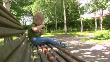 Dondurmalı bankta oturan çocuk.