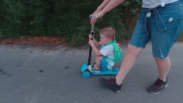 Мальчик на скутере с матерью — стоковое видео