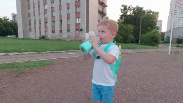 Menino com uma garrafa cospe — Vídeo de Stock