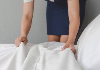 Otelin oda servisini kapat, yatak yap, otel odasında kadın hizmetçi yatağı yap.