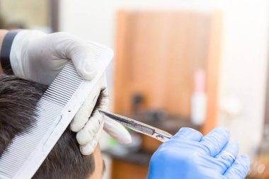 Genç çocuk berber dükkanına kuaföre gidiyor, çocuk kuaföre saç tıraşı oluyor, makas kullanıyor ve iletişim kuruyor.