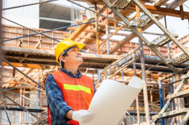 İnşaat alanında proje tasarısı tutan mühendis / işçi.