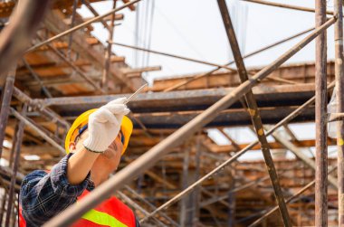 İnşaat alanındaki projeyi kontrol eden ve planlayan mühendis elinde kağıt tutan ve ileriye bakan adam.