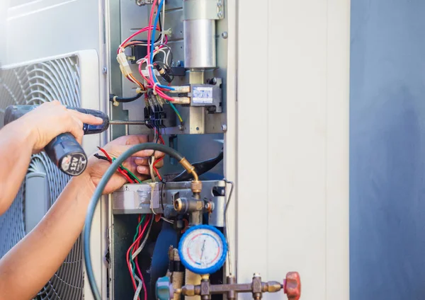 Male technician hands using a screwdriver fixing modern air conditioner, repairing and servicing, Maintenance and repairing concept