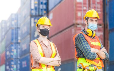 Başarı Takım Çalışması Konsepti, iş adamları mühendisi ve işçi takımı Coronavirus 'a karşı koruma maskesi takıyor ve kolları çapraz konteynır kutusunun arka planında bulanıklık yarattı.