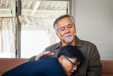 Kıdemli Asyalı baba oturma odasında yetişkin oğluna tavsiye veriyor. Mutluluk aile kavramları.