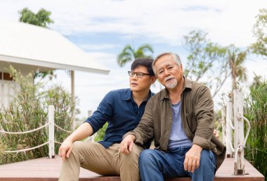 Asya 'nın kıdemli babası ve orta yaşlı oğlu birlikte oturur dışarıda rahatlar, Asyalı mutlu aile kavramları.