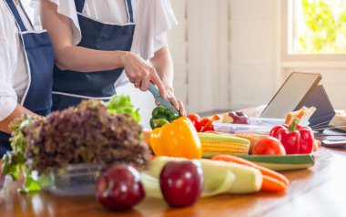 Kıdemli Asyalı anne ve orta yaşlı kız mutfakta birlikte yemek pişiriyorlar.