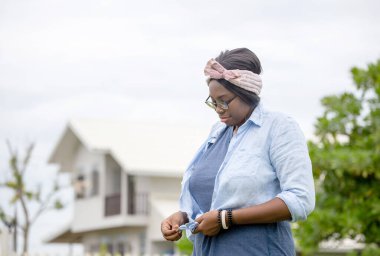 Neşeli Afro-Amerikalı kadın ayakta ve dışarıda gülümsüyor.