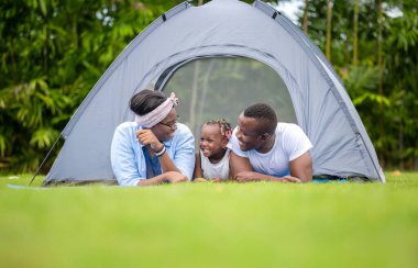 Neşeli Afro-Amerikan ailesi parkta eğleniyor, anne-baba-kız açık havada kamp yapıyor, mutluluk aile kavramları...