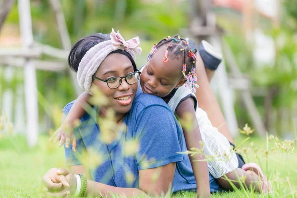 African american girl playing on the back of her mother, Happy mother and daughter laughing together outdoor