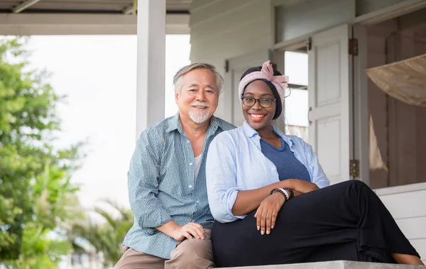 Senior asian man and cheerful african american woman sitting relax and looking at camera