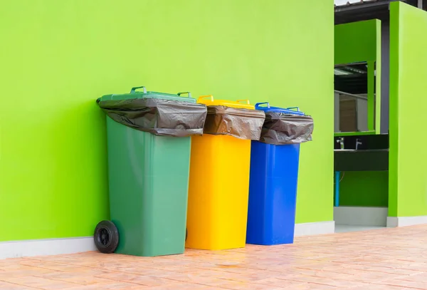 Group of colorful recycle bins green background, Different colored bins for collection of recycled materials. Garbage bins with garbage bags of different colors. Environment and waste management concept.