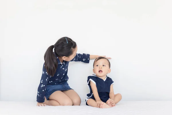 妹は弟の成長を測定します 子供たちはベッドで遊んで 幸せな家族のコンプ — ストック写真