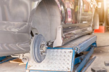 Tekerlek hizalama cihazını tamir eden tamirci yeni lastik değiştiren bir arabanın tekerine takıyor.