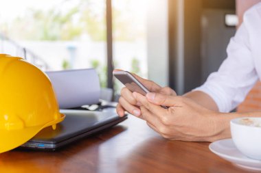 Gelişigüzel genç iş adamının seçici odak noktası kahve bulanık arka planlı cep telefonu kullanan eli.