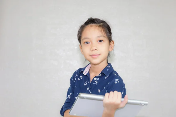 Little kid girl typing at wireless computer keyboard, Portrait of Happy child looking at camera with blurred background