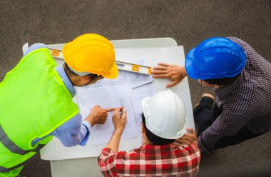 Mimarlık Mühendisliği Planlama Grubu proje ortakları inşaat sahasında, İnşaat şantiyesi ofis takım çalışması konseptinde toplanıyor.