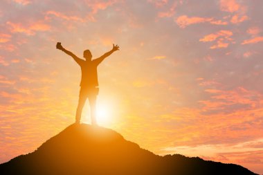 İnsanoğlunun silueti başarıyı kutluyor dağın tepesinde gün batımı gökyüzü arka planı, spor ve aktif yaşam kavramı.