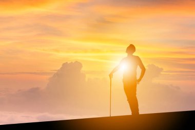 Elinde golf sopaları, elinde kırpma yolu olan ve gökyüzüne bakan iş adamının silueti. Başarı ve büyük bir konsept..