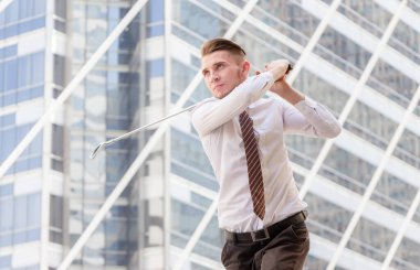 Elinde golf sopaları olan bir iş adamı gökyüzüne bakıyor, başarılı oluyor ve büyük bir konsept düşünüyor..