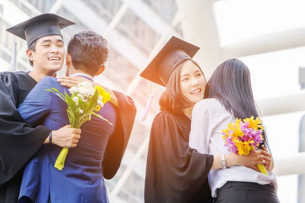 Close up of young graduate man and graduate woman with clipping path hugging friend at graduation, education concept