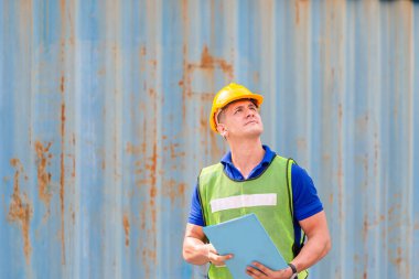 İşçi pano kontrol listesi tutuyor ve kargodan konteynır kutusunu kontrol ediyor