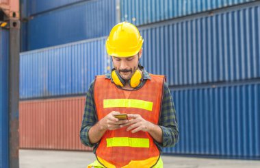 Mühendis cep telefonu kullanıyor, endüstri işçisi endüstriyel konteynırlarda cep telefonu kullanıyor.
