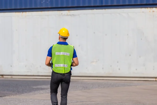 Foreman worker in hard hat and safety vest at containers cargo