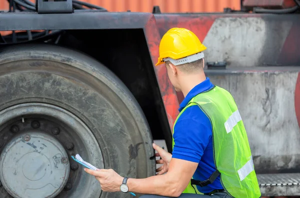 Tamirciler kargo konteynerinde tekerlekleri kontrol ediyor. Profesyonel teknisyen forklift ön kontrolü, güvenlik konsepti..