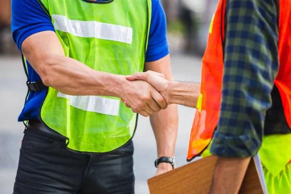 Fatory worker handshake with blurred construction site, Success and Teamwork concept