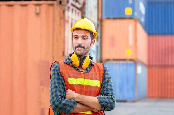 Portrait of Engineer man in hard hat and safety vest, worker with protective headphones at construction site