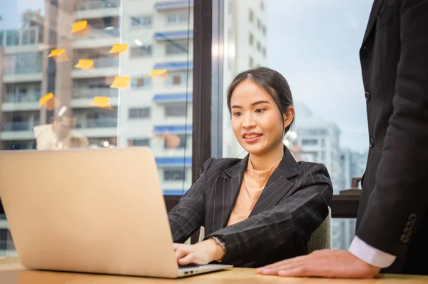 Business woman typing on laptop. Boss standing near employee and controlling process