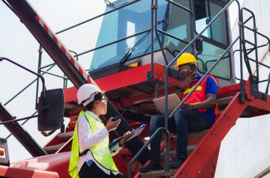 Kask ve güvenlik yeleği giyen kadın ustabaşı elinde pano kontrol listesi ve konteynır taşıyıcıları üzerinde poz veren iki yönlü komik telsiz çalışanı, Mühendis takımı kontrol kutuları kargo, başarı ve takım çalışması konseptlerinden yüklüyor.
