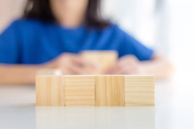 Masanın üzerinde dört boş tahta küp ve bulanık kız arka planı var. Model, şablon, pankart için.