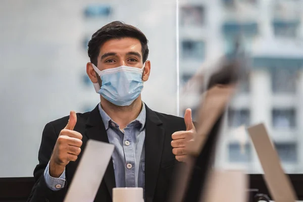 Young businessmen wear face masks with giving thumbs up as a sign of success