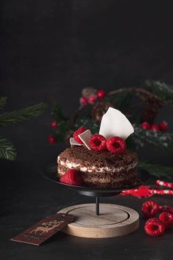 Yılbaşı süslemesinde ahududulu üç çikolatalı kek. koyu arkaplanda