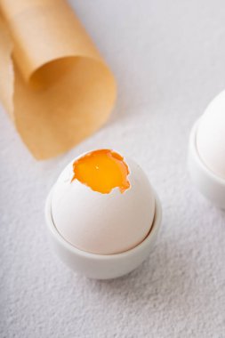Seçici odaklanma. Beyaz seramik yumurta standında, arka planda taze tavuk yumurtası.
